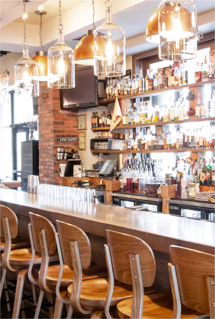 Rye Leawood Bar, with bright light streaming through the bottles on the shelves. Used as decoration on the Leawood Contact Page.