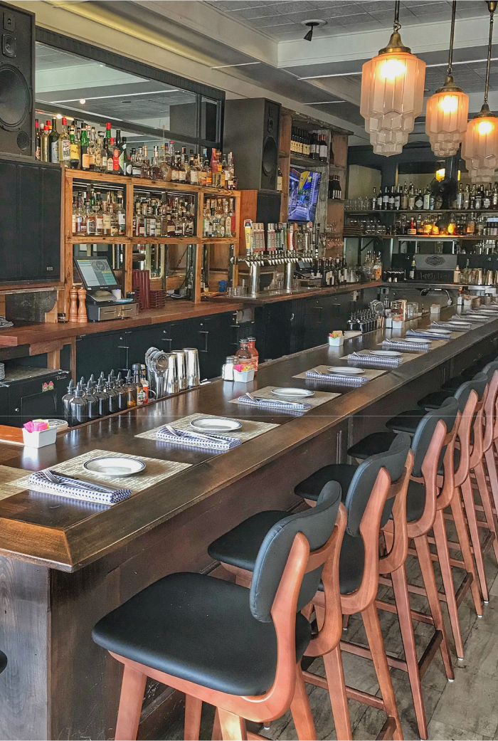 The Rye Plaza bar, set up for service with placemats, plates, silverware, and napkins. Used as decoration on the Plaza Contact Page.